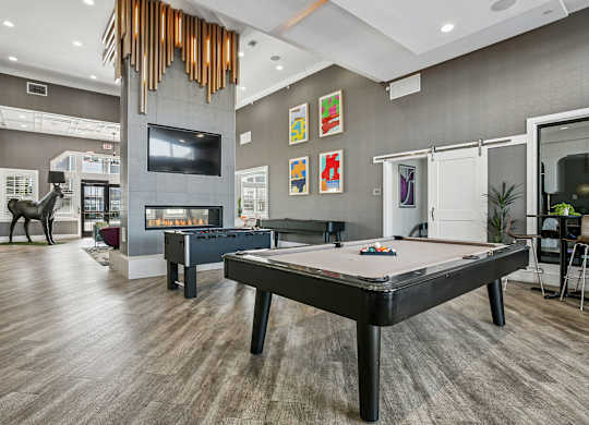 A pool table is in the middle of a room with a tv and a fireplace.