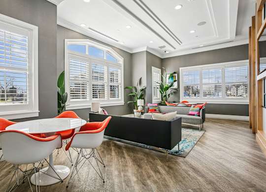 A modern dining room with a white table and orange chairs.
