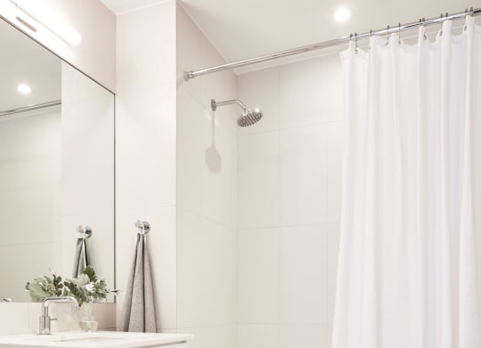 a white bathroom with a shower and a sink and a mirror
