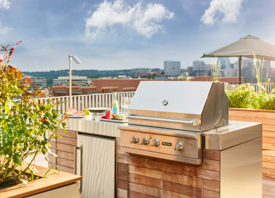 a barbecue grill on a deck with a city in the background