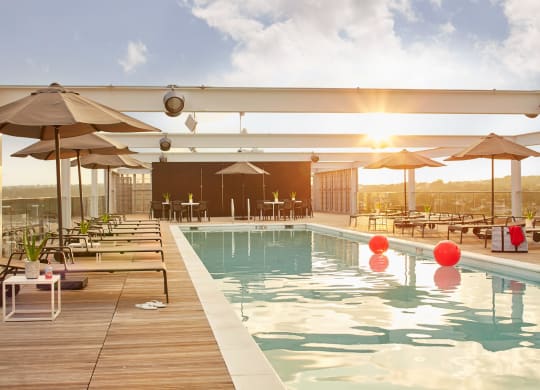 a swimming pool on the top of a building with chairs and umbrellas