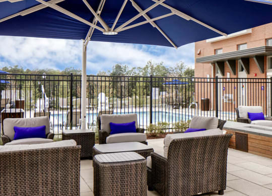 A patio with a table and chairs and a pool in the background.
