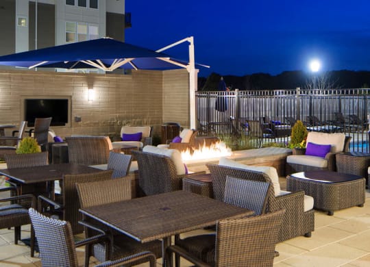 Patio with outdoor seating and view of  pool at night