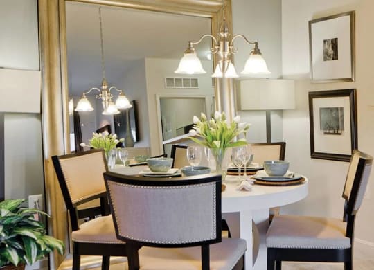 Dining Room Space with a Large Gold Rimmed Mirror, tan carpeting, and a four-person black and white dining set at Chesapeake Ridge, Maryland