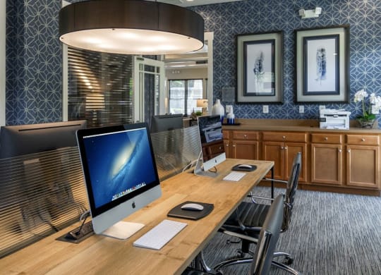 Business Lounge with pattered navy wall paper and wooden table with desktop computers at Chesapeake Ridge, Maryland