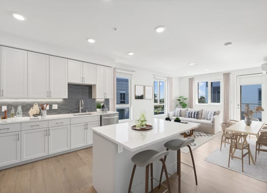 a white kitchen with a white island and a living room