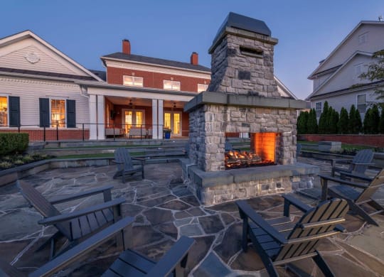 a stone fireplace in the center of a patio with chairs