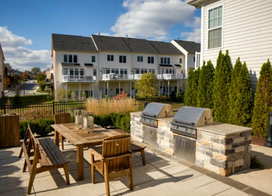a patio with a table and chairs and a barbecue grill