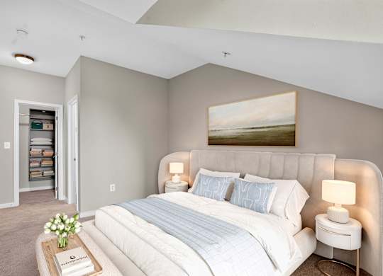 Virtually staged upstairs bedroom at Enclave at Emerson with a vaulted ceiling, neutral carpeting, an upholstered bed and an open closet.