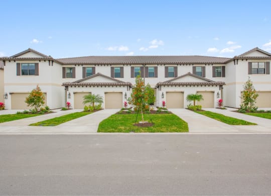 a large white house with two garage doors and a driveway at Fiore Townhomes, Florida