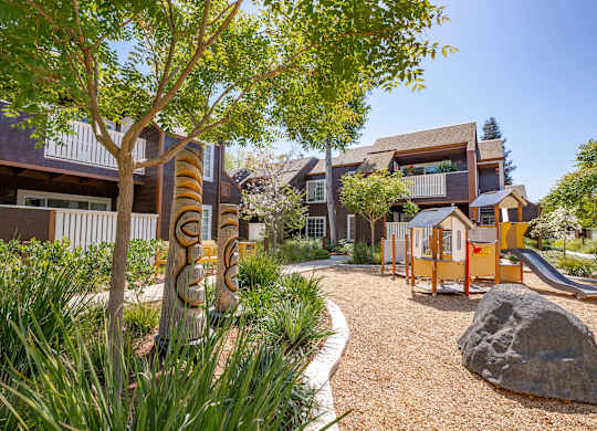 A playground area with a slide and a rock in the foreground.