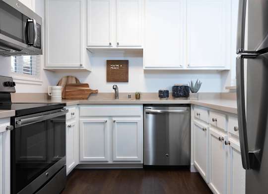 A kitchen with white cabinets and a wooden cutting board.