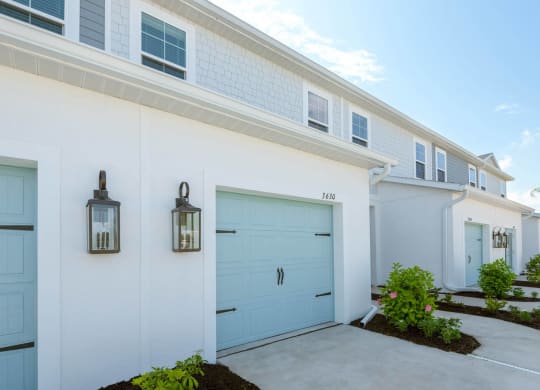 a white and blue house with two blue garage doors