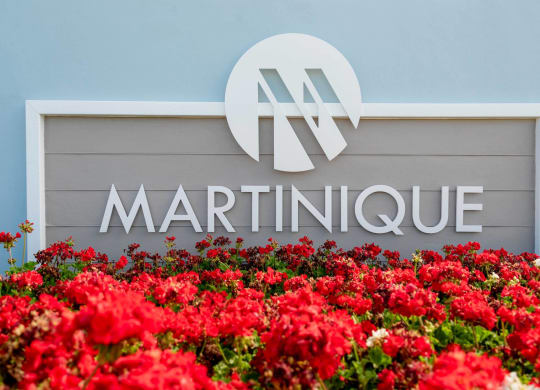 a sign for martinique with red flowers in front of it