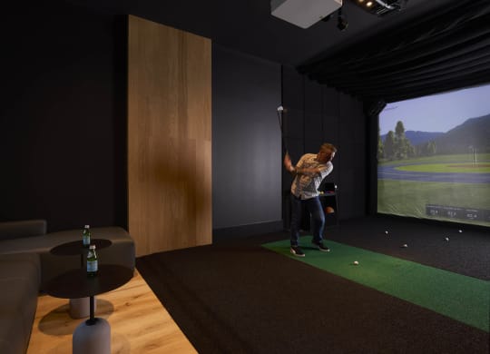 a man playing golf on a simulator in a living room
