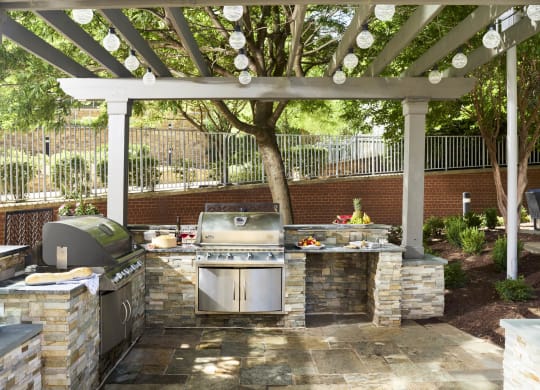a outdoor kitchen with a grill and a pergola