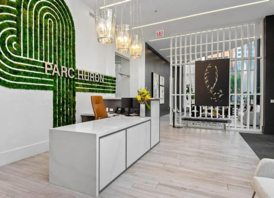 a reception area with a green logo on the wall and a white reception desk