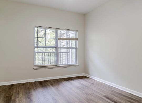 a bedroom with white walls and a window and wood floors