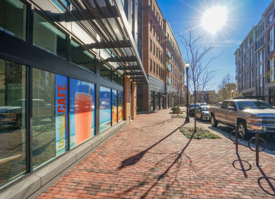 a city street with a brick sidewalk and a row of buildings