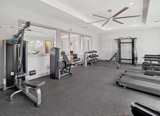 A spacious gym with a variety of equipment including treadmills, weights, and a bench press.
