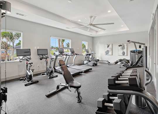 A spacious gym with a variety of equipment including treadmills, stationary bikes, and weight machines.