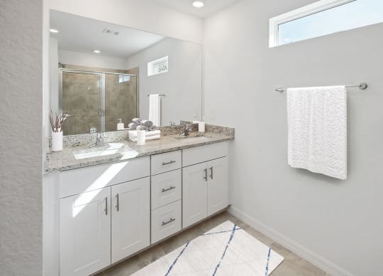 a bathroom with white cabinets and gray walls