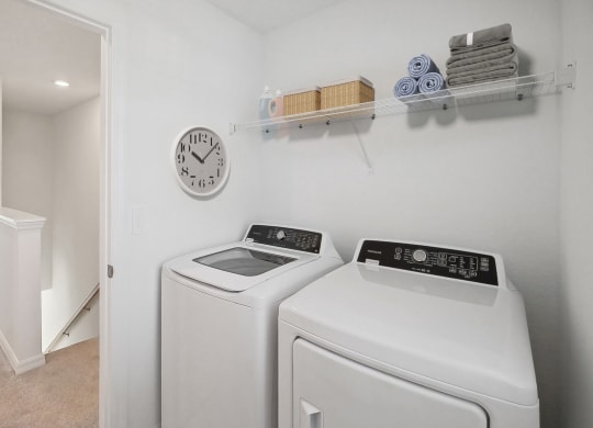 a laundry room with a washer and dryer and a clock on the wall
