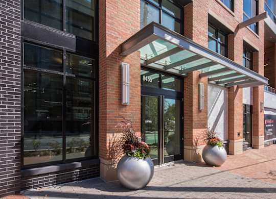 A modern building with a glass entrance and two large planters in front.