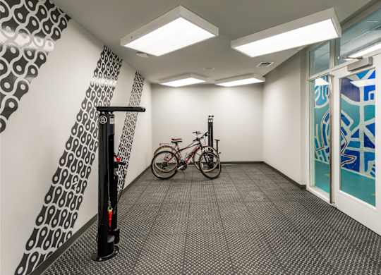 A bicycle is parked in a hallway with a black and white patterned wall and a glass door.
