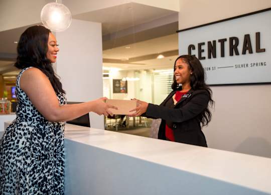 Two women shaking hands in front of a sign that says Central.