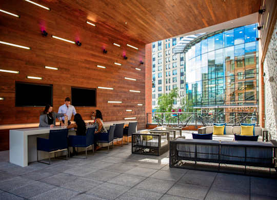 A group of people are sitting at a bar in a room with wooden walls.
