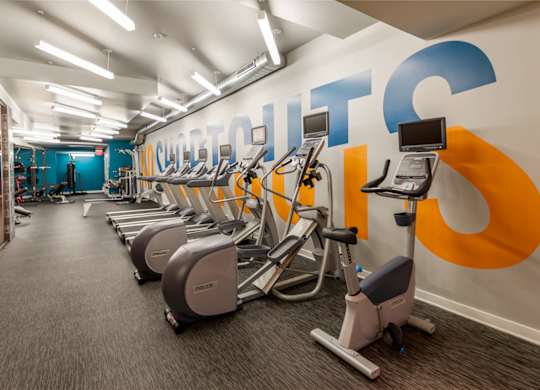 A gym with a row of exercise bikes and a wall with the word