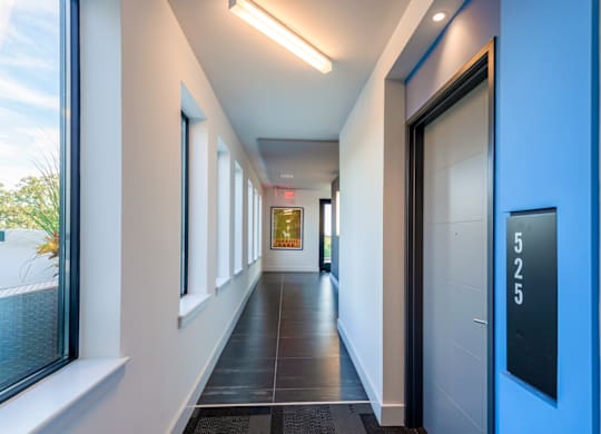 A long hallway with a blue door and a sign that says 525.