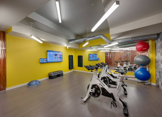 A gym with a yellow wall and exercise equipment.