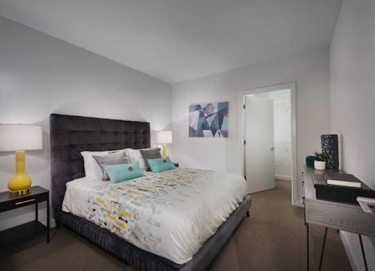 A bedroom with a large bed and a nightstand with a lamp.