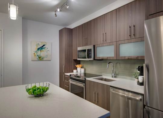 A modern kitchen with a stainless steel refrigerator, microwave, and oven.