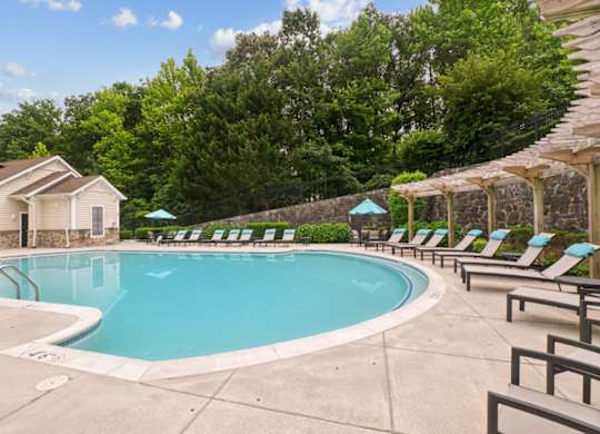 A large swimming pool surrounded by lounge chairs and umbrellas.