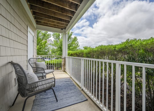 a balcony with two chairs and a view of the water