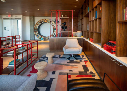 a living room with a chair and a rug in front of a bookshelf
