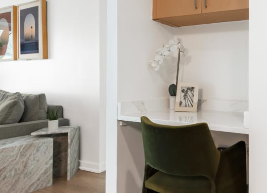 a desk with a green chair in a living room with a couch
