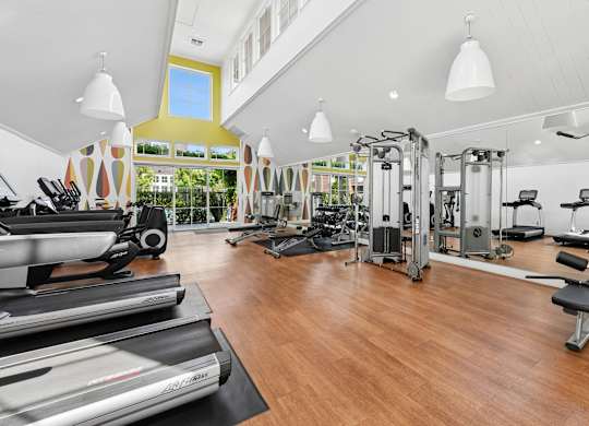 Spacious fitness center at Grove Apartments featuring cardio machines, weight equipment, and mirrored walls.