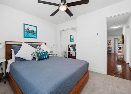 Bedroom at Grove Apartments with modern furnishings, mirrored closet doors, and ceiling fan.