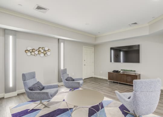 a living room with chairs and a table and a television