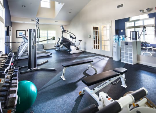 a gym with cardio equipment and weights on the floor