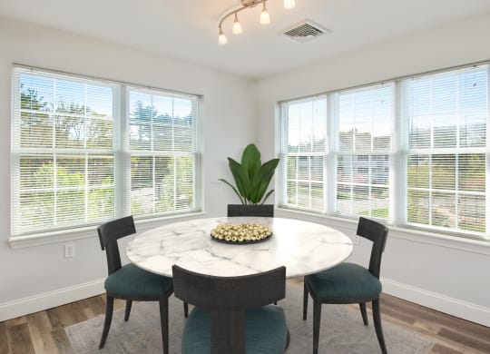 a dining room with large windows and a marble table and chairs