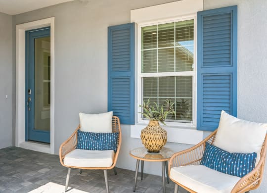 a porch with two chairs and a table and blue shutters at Marisol, Bradenton