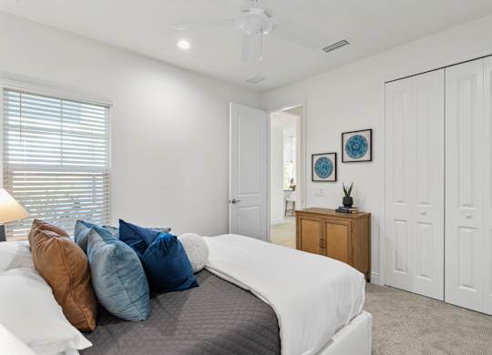 A bedroom with a bed, pillows, and a ceiling fan at Marisol in Lakewood Ranch, FL