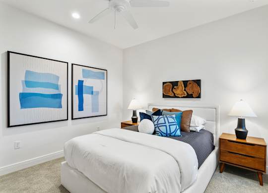 A bedroom with a bed, two lamps, and two framed artworks on the wall at Marisol in Lakewood Ranch, FL