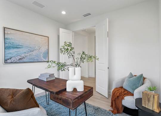 A living room with a brown chair, a coffee table, a couch, and a painting on the wall at Marisol in Lakewood Ranch, FL
