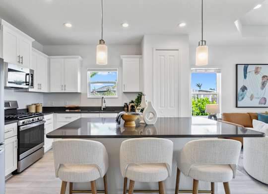 A modern kitchen with white cabinets and a black countertop at Marisol in Lakewood Ranch, FL